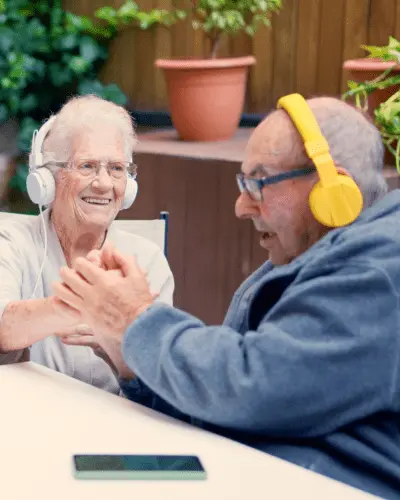 Elderly couple wearing headphones, smiling and enjoying music together.