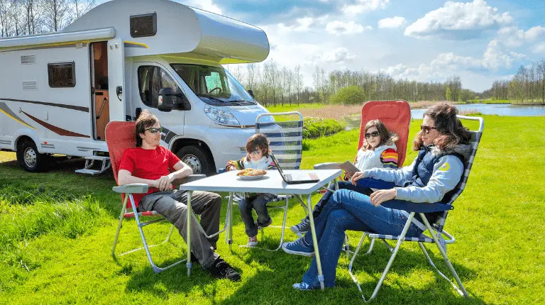 Family enjoying a sunny day outside their campervan, symbolising financial freedom and leisure.