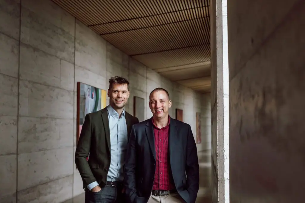 Scott and Phil, financial planners for Wealthlab, standing together in professional attire in a modern office space.