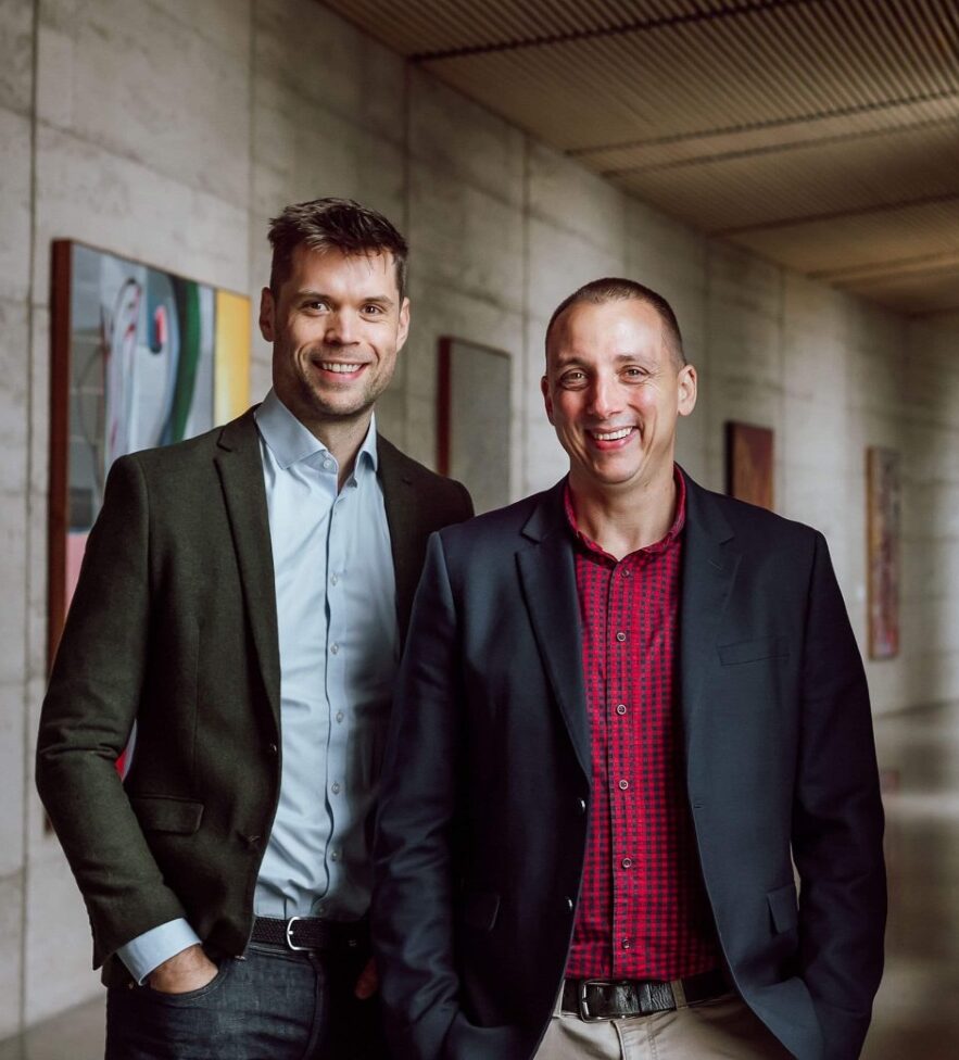 Scott and Phil, financial planners for Wealthlab, standing together in professional attire in a modern office space.